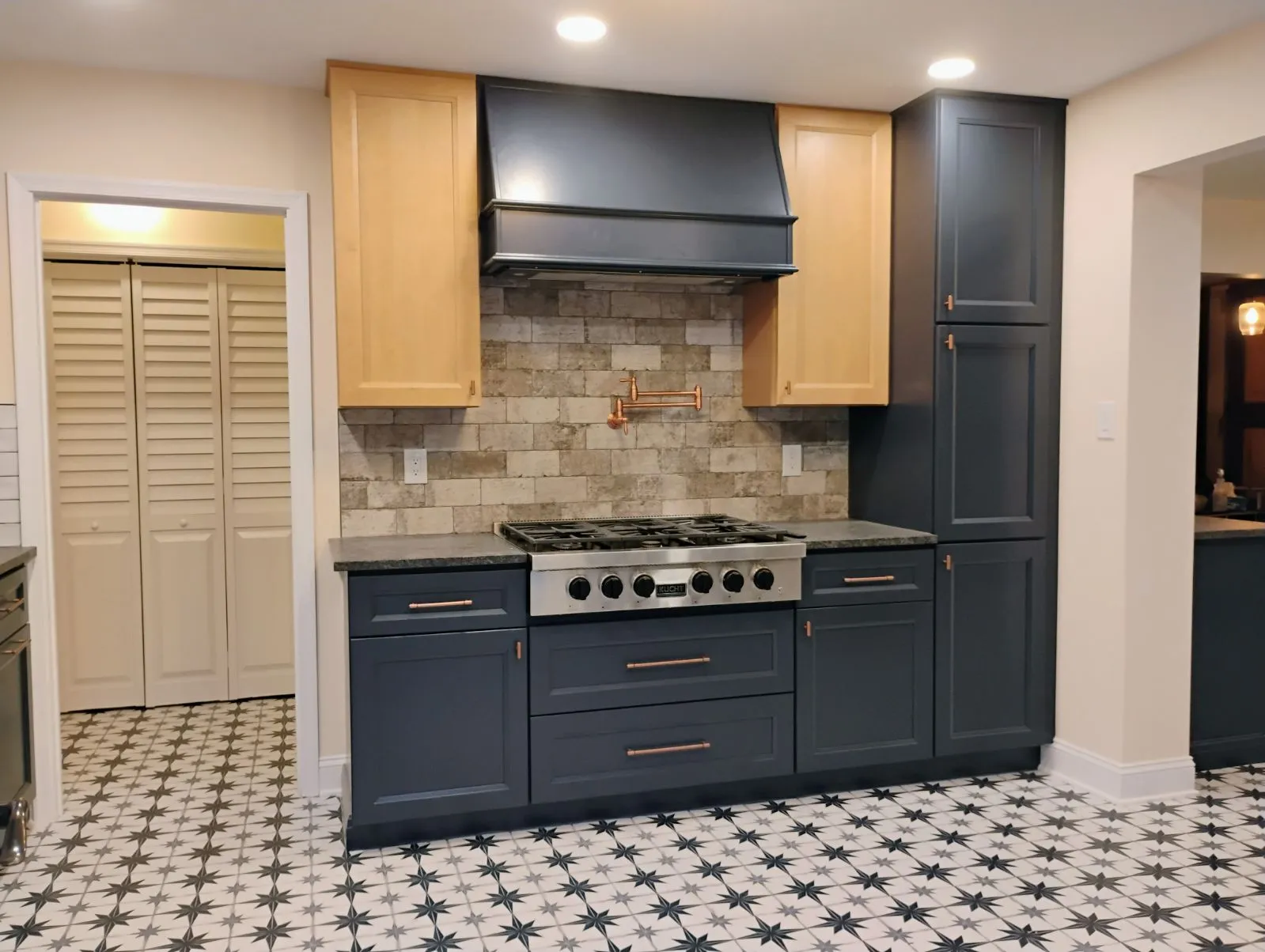 Kitchen with navy lower cabinets, wood uppers and star pattern floor tile, by Kubat Construction