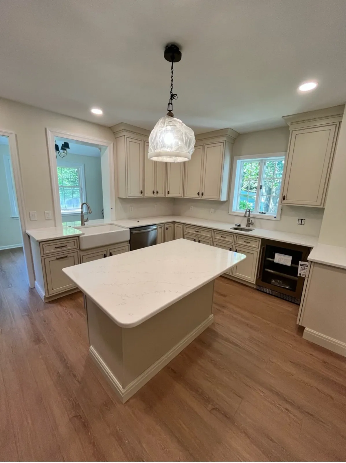 White kitchen with an island and a glass pendant light, by Kubat Construction