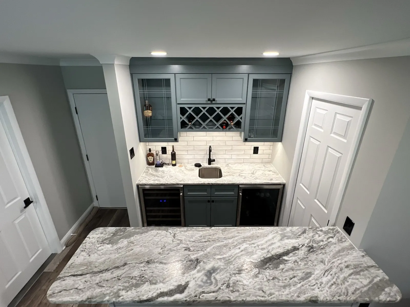 Kitchen island with a marble-look top and a built-in wine rack, by Kubat Construction