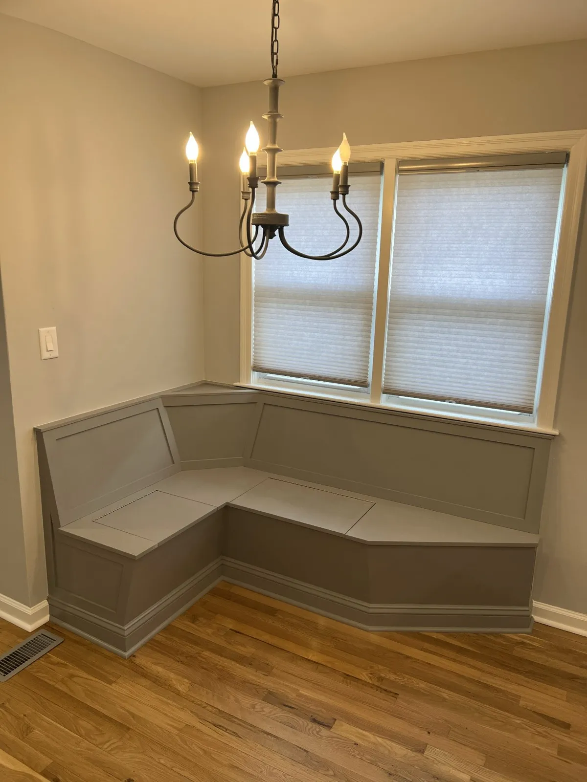 Built-in breakfast banquette under a chandelier, by Kubat Construction
