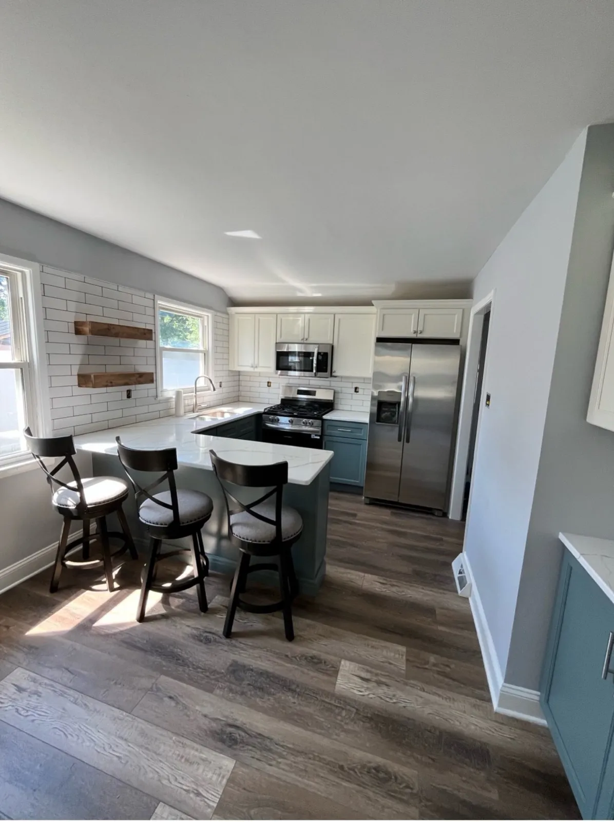 Kitchen with blue-gray cabinets and a farmhouse table, by Kubat Construction